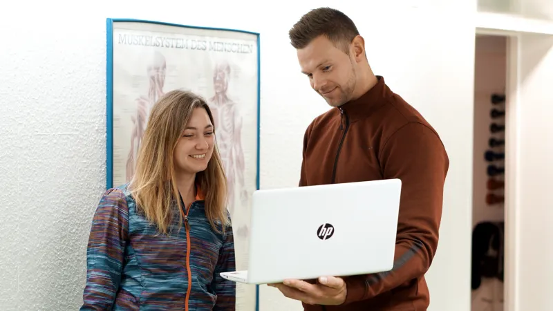 Maßgeschneiderte Trainingspläne und 1:1 Fitnesscoaching Personal Coach zeigt Klientin Trainingsplan